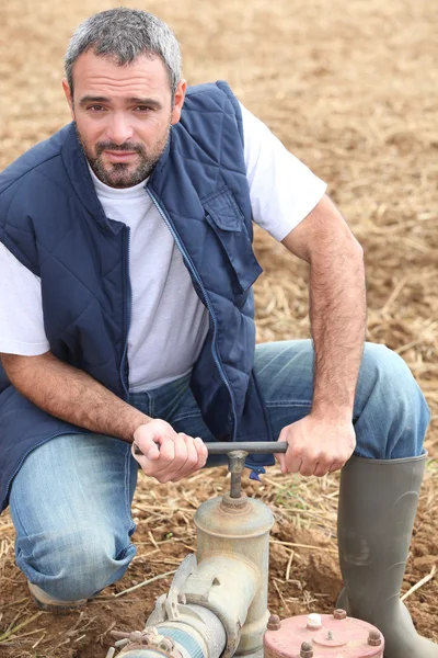 Agricultor abrindo um tubo de água — Fotografia de Stock