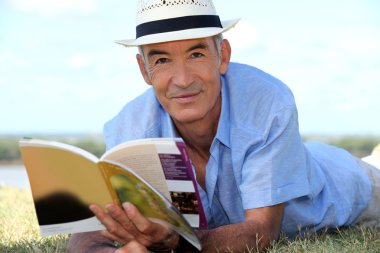 Elderly man reading a book outside clipart