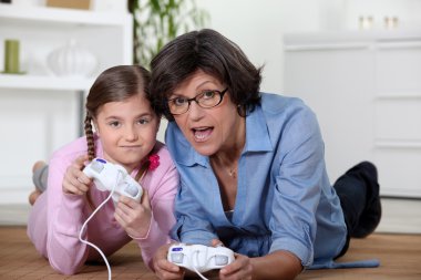 Grandmother playing a video game with her granddaughter clipart