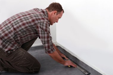 Tradesman laying down linoleum flooring clipart