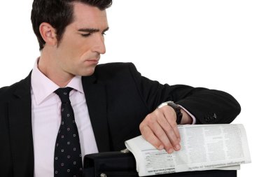 Man with newspaper looking at watch clipart