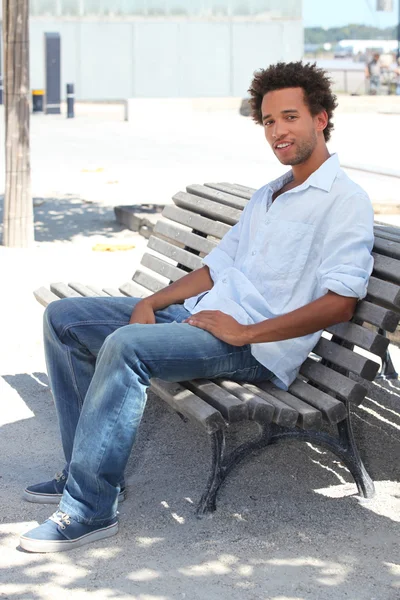 Junger Mann sitzt auf einer Bank — Stockfoto