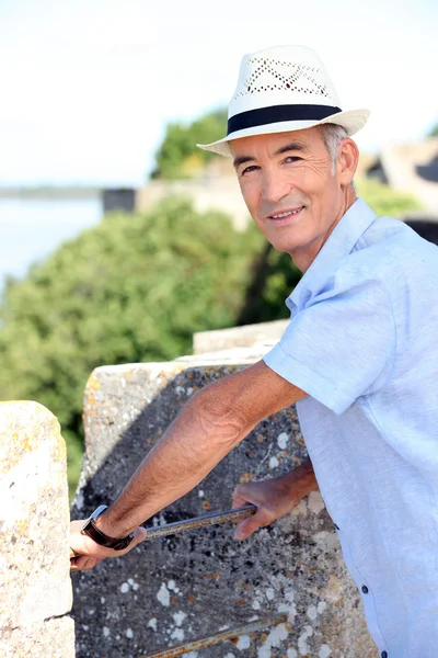 Old man on holiday leaning against wall — Stock Photo, Image