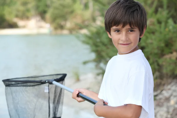 Petit garçon au bord d'une rivière avec un filet d'atterrissage — Photo