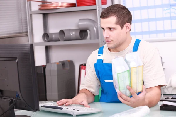 Man checking plumbing products on a computer database — Stock Photo, Image