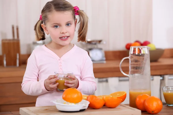 Liten flicka gör apelsinjuice. — Stockfoto
