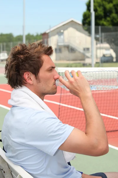 Tenista pití na lavičce — Stock fotografie