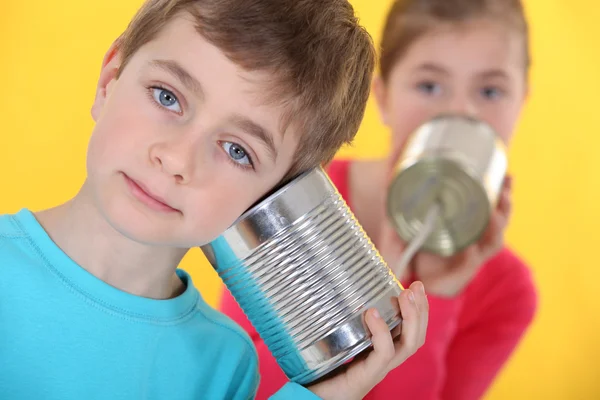 Two kids talking through linked cans. — Stock Photo, Image