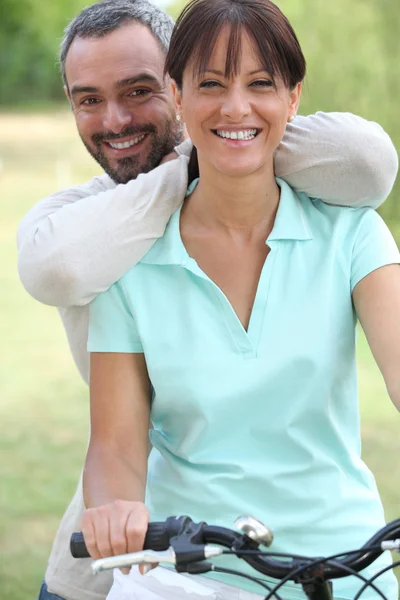 Homme et femme souriants sur un vélo — Photo