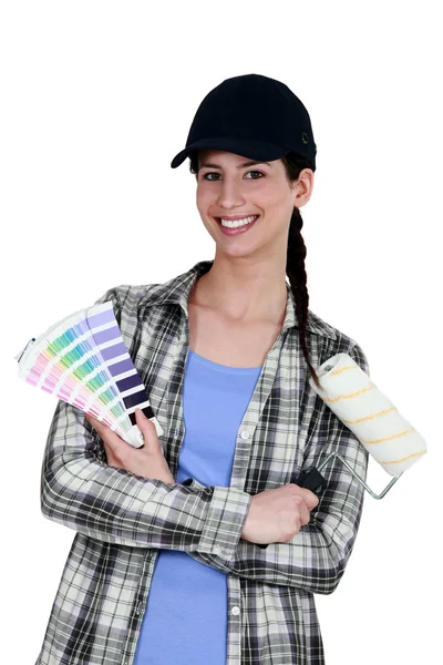 Pintora femenina sosteniendo un cepillo de rodillos y una carta de colores — Foto de Stock