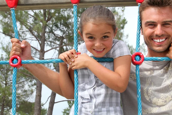 Young girl on a climbing frame with her dad — Stock Photo, Image