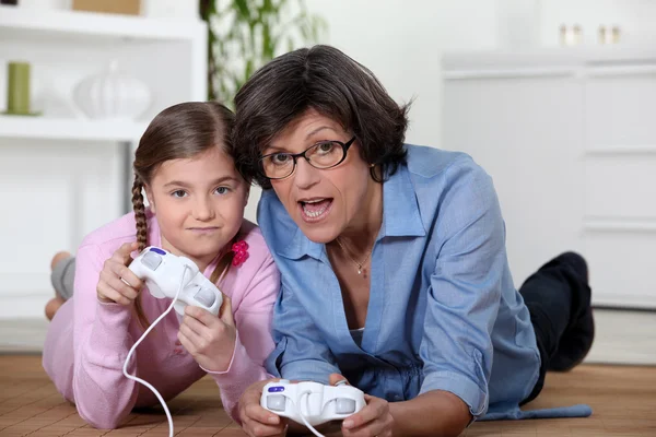 Afspelen van een video game met haar kleindochter grootmoeder — Stockfoto
