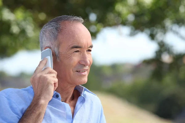 Oude man met een mobiele telefoon — Stockfoto