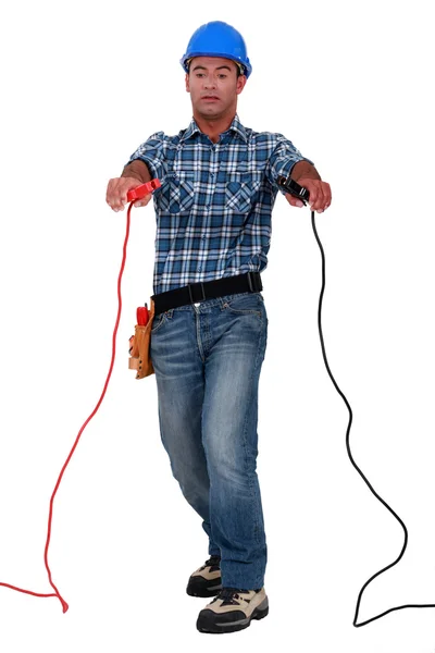 Tradesman holding jumper cables — Stock Photo, Image