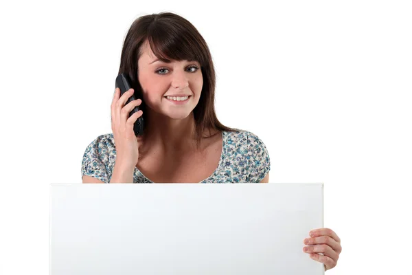 Ung kvinna med en mobiltelefon och en styrelse tomt för ditt meddelande — Stockfoto