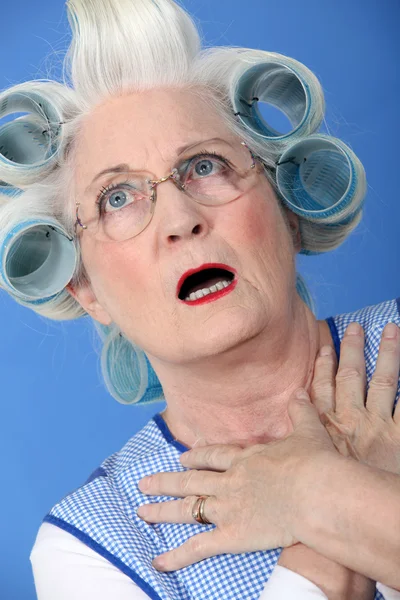 Senior woman with curlers in her hair looking very surprised — Stock Photo, Image