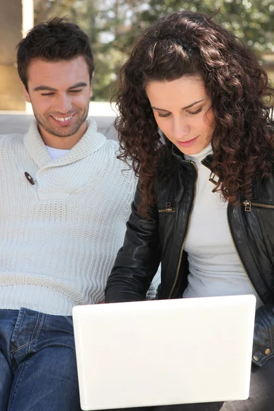 Casal usando um laptop ao ar livre — Fotografia de Stock
