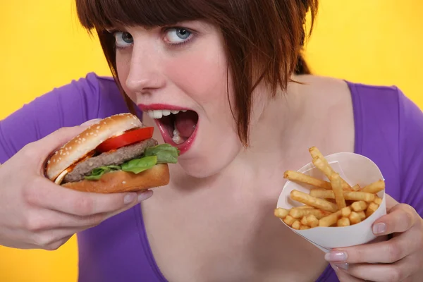 ハンバーガーとチップを食べる女性 — Stock fotografie