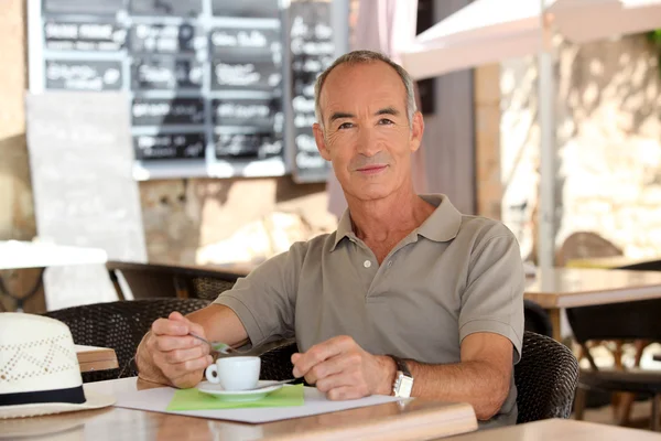 Człowiek pije kawę poza kawiarnią — Zdjęcie stockowe