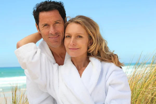 Paar ontspannen op het strand in handdoek gewaden — Stockfoto