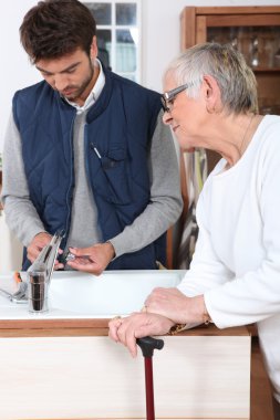 Young man fixing faucet for older woman clipart