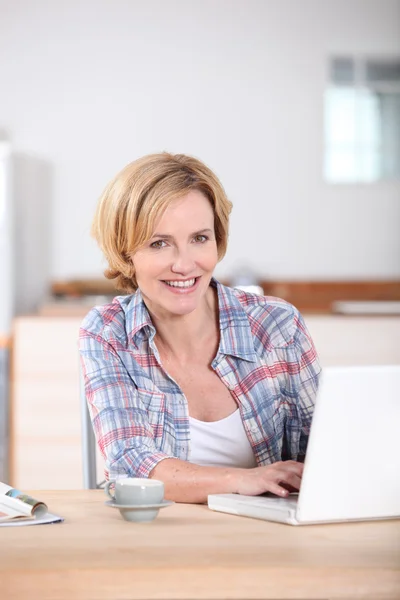 Donna seduto in cucina digitando sul computer portatile — Foto Stock