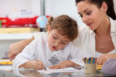 Teacher watching her pupil colouring a drawing clipart