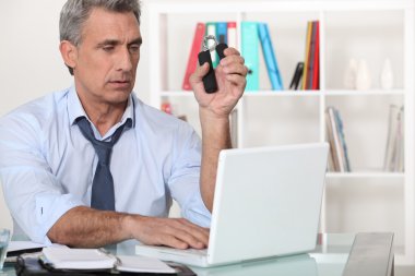 Man squeezing hand grippers while reading an e-mail clipart