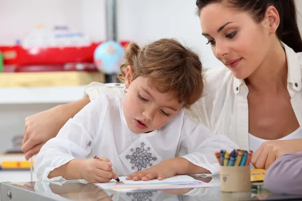 Leraar kijken haar leerling kleuren van een tekening — Stockfoto