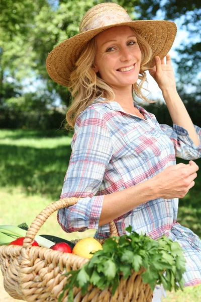 Vrouw die lacht met stro hoed en mand met fruit. — Stockfoto