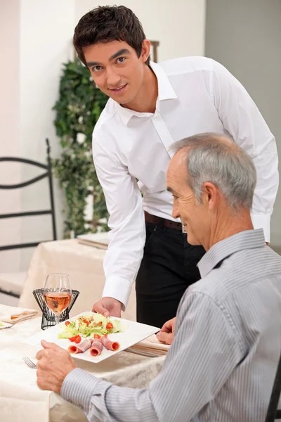 Jonge ober serveren een oudere klant — Stockfoto