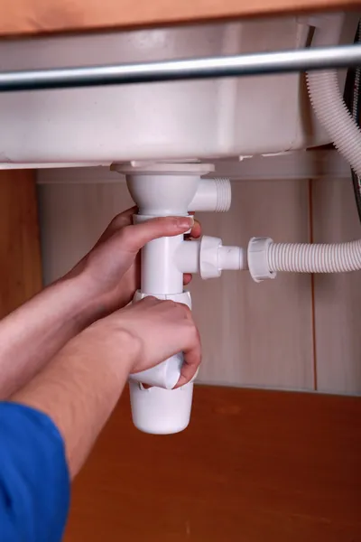 Plumber fitting the waste pipe to a kitchen sink — Stock Photo, Image