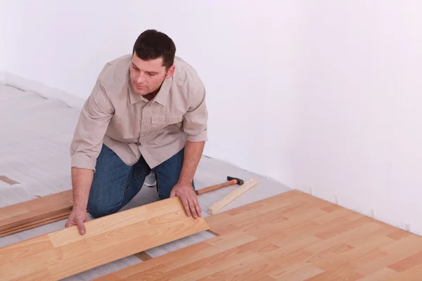 Homem que estabelece piso laminado no apartamento — Fotografia de Stock