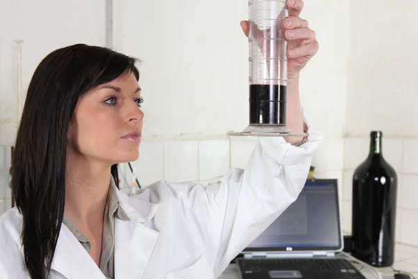 Femme vérifiant le vin dans un laboratoire — Photo