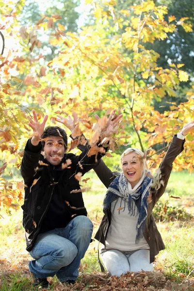 Man en vrouw gooien bladeren — Stockfoto