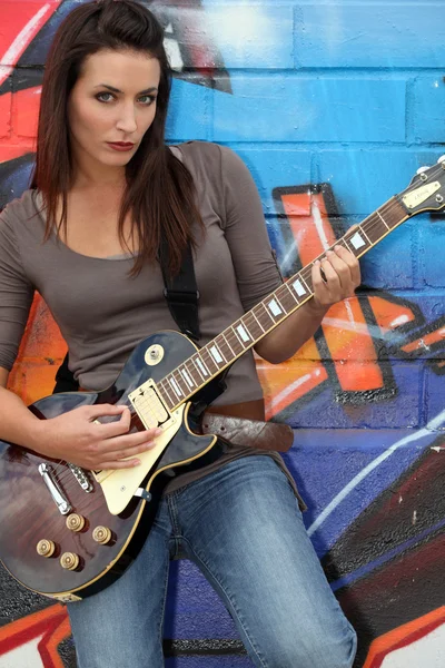 Kobieta gitarzysta stał przez ściany malowane — Zdjęcie stockowe