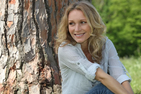 Vrouw zitten tegen een boom — Stockfoto