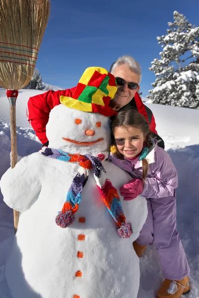 Vater und Tochter bauen Schneemann — Stockfoto