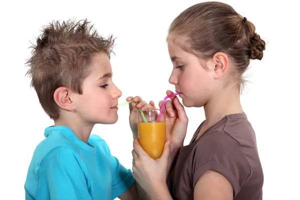 Двоє дітей діляться апельсиновим соком — стокове фото
