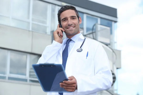 Чоловік лікар за межами лікарні робить телефонний дзвінок — стокове фото