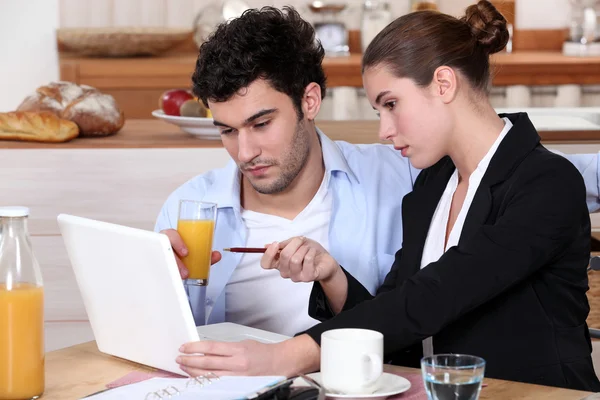 Casal tomando café da manhã e trabalhando em um laptop — Fotografia de Stock