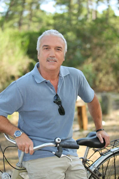 Relaxed senior man leaning on his bike — Stock Photo, Image