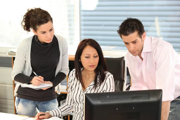 Three colleagues gathered around computer screen — Stock Photo, Image