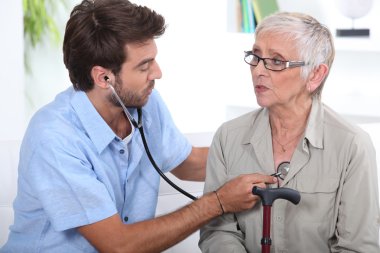 Medic listening to a senior woman's chest clipart