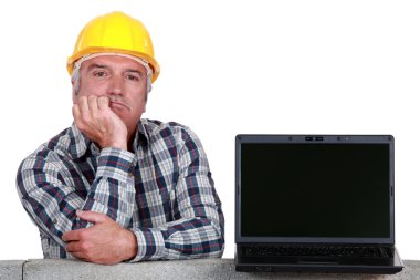 Senior craftsman posing next to a laptop clipart