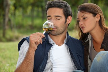 Couple tasting wine in field clipart