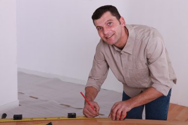 Tradesman marking a measurement on a wooden plank clipart