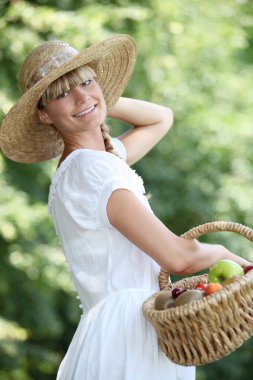 Carefree woman with a straw hat and wicker basket full of fruit clipart