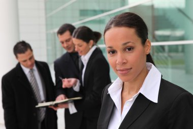 Woman standing with colleagues in front of an office building clipart