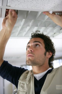 Man putting up a suspended ceiling clipart